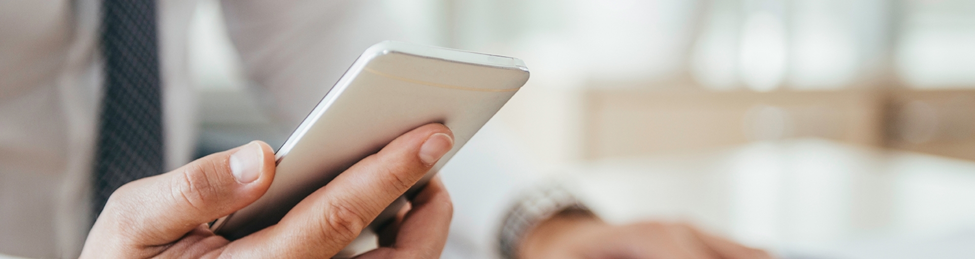 Midsection Of Businessman Using Laptop While Holding Mobile Phone On Table In Office 